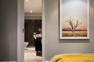 a bathroom with a painting of a tree on the wall at Schafhalle in Hepburn Springs +11 photos