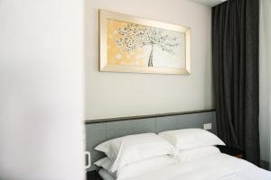 a bed with white pillows and a picture on the wall at Tingjian Lingyin Alanruo Design Homestay in Hangzhou