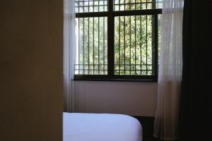 a bedroom with a window with white curtains and a bed at Tingjian Lingyin Alanruo Design Homestay in Hangzhou