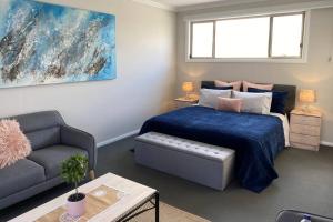 een slaapkamer met een bed, een bank en een raam bij Mountain Views (3 min drive to beach) in Gerringong