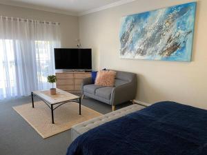 a living room with a bed and a couch and a tv at Mountain Views (3 min drive to beach) in Gerringong