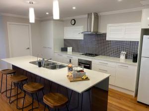 a kitchen with a sink and a counter with stools at Mountain Views (3 min drive to beach) in Gerringong