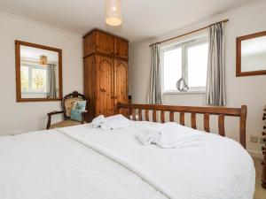 a bedroom with a white bed with two white towels on it at Angarrack Farmhouse in Hayle