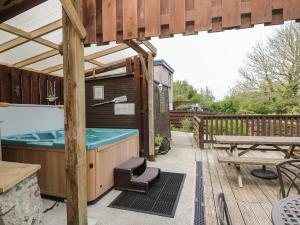 a hot tub on a deck with a picnic table at Angarrack Farmhouse in Hayle