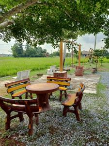 a group of wooden tables and chairs under a tree at Heal Inn Roomstay - Islam Guest in Kangar