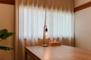 eine Lampe auf einem Tisch neben einem Fenster in der Unterkunft R-house 4th in Tokio