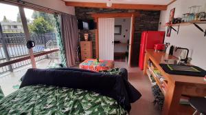 a living room with a bed and a kitchen with a window at The Poolhouse in Matamata