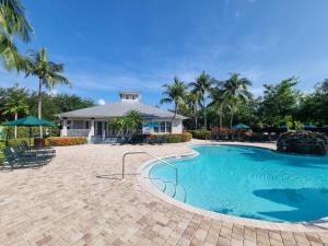a swimming pool in front of a house with palm trees at Greenlinks 923 at Lely Resort - Luxury 2 Bedrooms & Den Condo in Naples