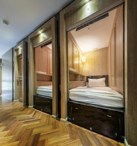 two bunk beds in a room with wooden floors at The poshtel Bangkok By Benya in Bangkok