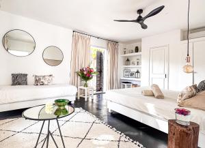 a white living room with two beds and a table at Guest House et Restaurant Sous le Badamier in Grand Baie