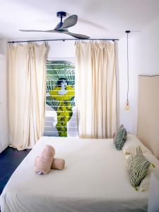 a bedroom with a white bed with two stuffed animals on it at Guest House et Restaurant Sous le Badamier in Grand-Baie