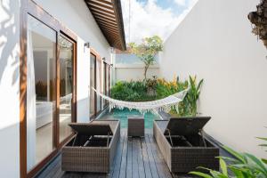 a patio with chairs and a hammock on a house at Anari Villas Kuta by The Wina Resorts in Legian