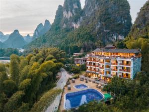a hotel with a pool and mountains in the background at Yangshuo Shanshuiyao Resort - Free Train Station Pick Up and Drop Off in Yangshuo