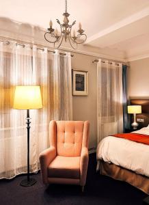een slaapkamer met een bed, een stoel en een lamp bij Excelsior INN in Turda