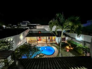 - une vue sur une maison avec une piscine la nuit dans l'établissement Casa Paris 481 - Sua Mansão na Praia do Morro, à Guarapari