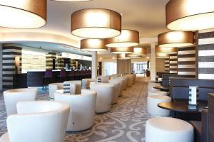 a restaurant with white chairs and tables and lights at Parc Hotel Alvisse in Luxembourg