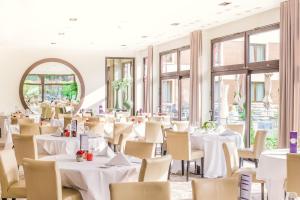 un ristorante con tavoli e sedie bianchi e uno specchio di Parc Hotel Alvisse a Lussemburgo