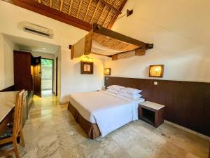 a bedroom with a bed and a table in a room at The Lagoon Bali Pool Hotel and Suites in Legian
