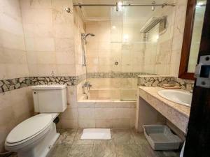 a bathroom with a toilet and a shower and a sink at The Lagoon Bali Pool Hotel and Suites in Legian