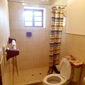 a bathroom with a toilet and a shower with a window at Hermosa casa de campo in Maras