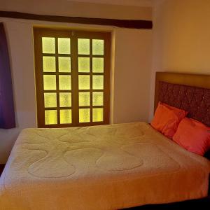 1 dormitorio con 1 cama con almohadas de color naranja y ventana en Hermosa casa de campo en Maras