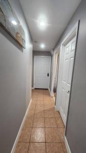 a hallway with a tile floor and a white door at Cozy King Bed, Free Parking! in Newark