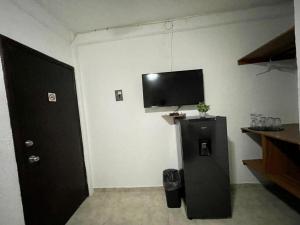 a room with a refrigerator and a tv on the wall at MAYAB Playa - 5Th. Ave in Playa del Carmen
