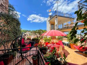 uma varanda com um pátio com cadeiras vermelhas e um guarda-sol em Terrazza Bella/sleeps 4/spoleto/car Not Necessary em Spoleto