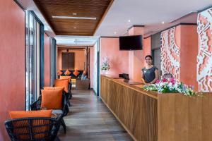 a woman standing at a reception desk in a hotel lobby at Mercure Samui Chaweng Tana in Chaweng