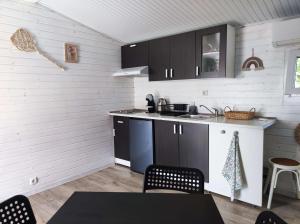 a kitchen with black cabinets and a table and chairs at Къщички Морски Светулки in Sinemorets