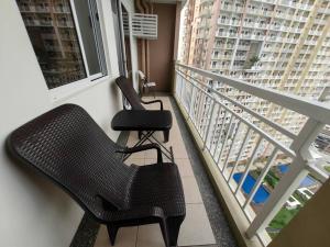 two chairs on a balcony with a view of a building at Infina Towers Cozy 2bedroom Condo in Manila