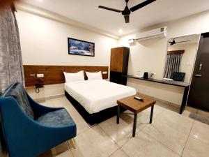 een slaapkamer met een bed, een tafel en een stoel bij Hotel Park Varaahi in Tirupati