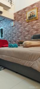 een groot bed in een kamer met een bakstenen muur bij SofiaSuite16, Plaza Azalea, Shah Alam in Shah Alam