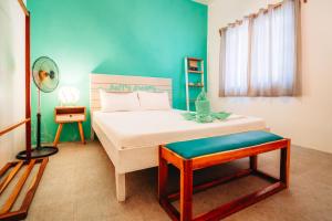 1 dormitorio con cama blanca y pared azul en My Green Hostel, en San Vicente