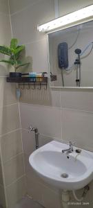 La salle de bains est pourvue d'un lavabo blanc et d'un miroir. dans l'établissement SofiaSuite16, Plaza Azalea, Shah Alam, à Shah Alam