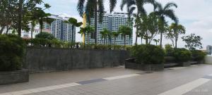 een betonnen muur met bomen en gebouwen op de achtergrond bij SofiaSuite16, Plaza Azalea, Shah Alam in Shah Alam