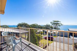 a balcony with a chair and the ocean in the background at 33 Gloucester St -huge holiday house in Nelson Bay with Pool, Air Con, WiFi, Foxtel and Stunning Water Views in Nelson Bay