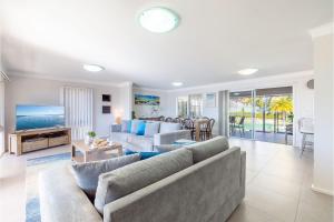 a living room with a couch and a table at 33 Gloucester St -huge holiday house in Nelson Bay with Pool, Air Con, WiFi, Foxtel and Stunning Water Views in Nelson Bay