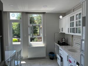 a kitchen with white cabinets and two windows at SISMAN’S in Soğuksu