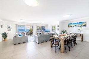 a dining room and living room with a table and chairs at 33 Gloucester St -huge holiday house in Nelson Bay with Pool, Air Con, WiFi, Foxtel and Stunning Water Views in Nelson Bay