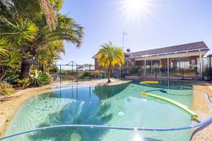 a swimming pool in a yard with palm trees at 33 Gloucester St -huge holiday house in Nelson Bay with Pool, Air Con, WiFi, Foxtel and Stunning Water Views in Nelson Bay