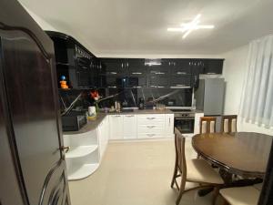 a kitchen with black cabinets and a table and a dining room at Casa Villa in Oradea