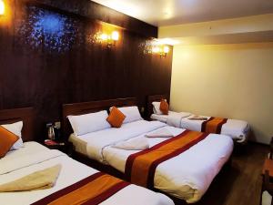 a hotel room with three beds with orange pillows at Royal Kings Hotel in Kathmandu