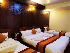 a hotel room with three beds with orange pillows at Royal Kings Hotel in Kathmandu