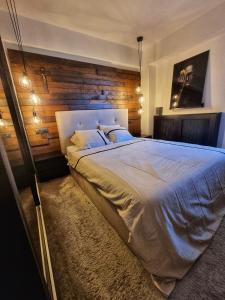 - une chambre avec un grand lit et un mur en bois dans l'établissement Eclipsei ApartHotel, à Popeşti-Leordeni