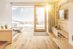 a room with a large window and a wooden door at Innermoser Bauernhof - Chalets in Molini di Tures
