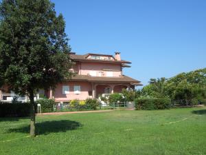 a large pink house with a tree in a yard at Apartment Circe in Sabaudia