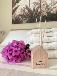 1 cama con toallas, flores púrpuras y caja de madera en B&B CIVICO CINQUE, en Pianella