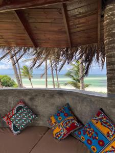 three pillows sitting on a couch in front of the beach at Gecko Resort in Watamu