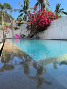 een zwembad met roze bloemen en een hek bij Villa Luna Sunset Beach in Gili Trawangan